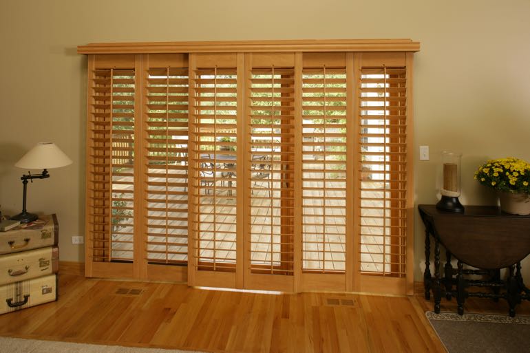 Faux wood shutters on sliding door leading to outdoor porch.